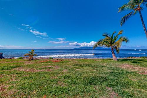 a beach with two palm trees and the ocean at Puamana 30-2 in Lahaina
