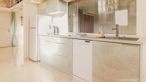 La cuisine blanche est équipée d'un évier et d'un réfrigérateur. dans l'établissement CondoNice, à Nice