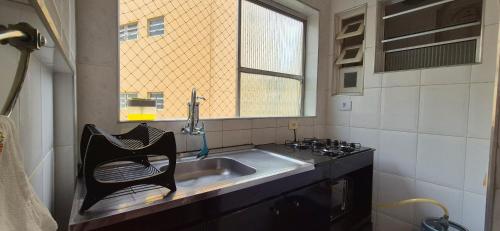 a kitchen with a sink and a window at ESD01- Ar Condicionado 5min a pé da Praia da Enseada, Apartamento in Guarujá