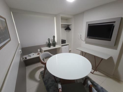 Habitación blanca con mesa blanca y TV en Trip Hotel Ubá - perto da Faculdade OZANAM COELHO e Eventos HORTO FLORESTAL, en Ubá