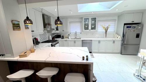 a kitchen with white cabinets and a counter with stools at Luxury Modern Retreat, Sauna, Theatre, Pool Table in Mississauga