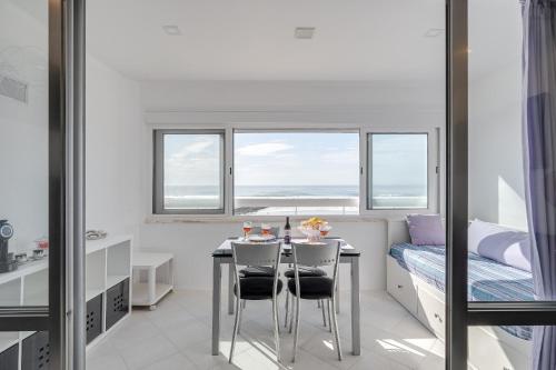 a dining room with a table and chairs and a bed at Horizonte Azul , Frente mar & Piscina in Costa da Caparica