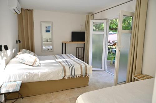 a bedroom with a bed and a sliding glass door at Hôtel La Petite Bohème in Le Lavandou