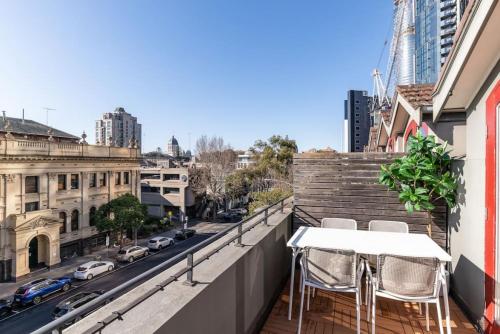 a table and chairs on a balcony with a city street at Bright stylish gem in central Melbourne in Melbourne