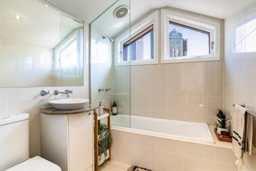 a bathroom with a tub and a sink and a bath tub at Bright stylish gem in central Melbourne in Melbourne