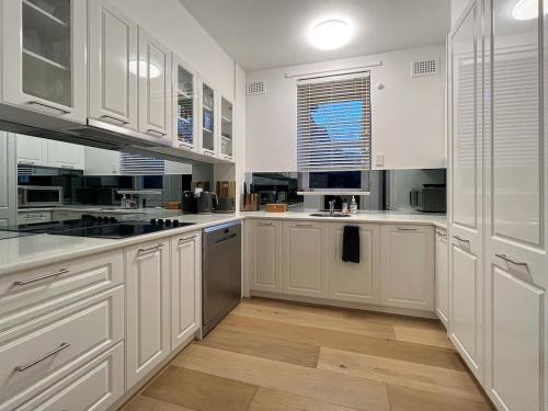 a white kitchen with white cabinets and a wooden floor at Affordable Luxury - CBD Wagga in Wagga Wagga