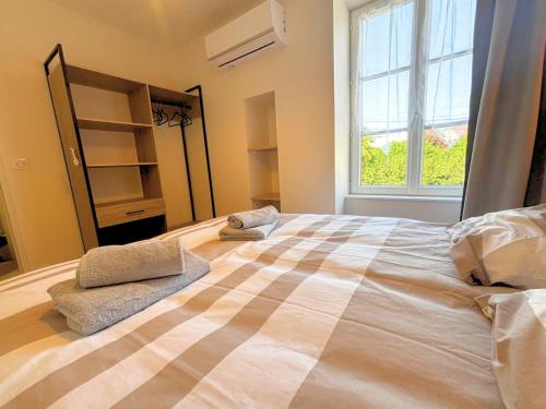 un grand lit dans une chambre avec une grande fenêtre dans l'établissement L'échapée verte Grand T3 avec climatisation, à Lons-le-Saunier