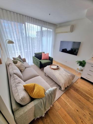 a living room with a couch and a tv at Regent Retreat Top floor apartment in Melbourne