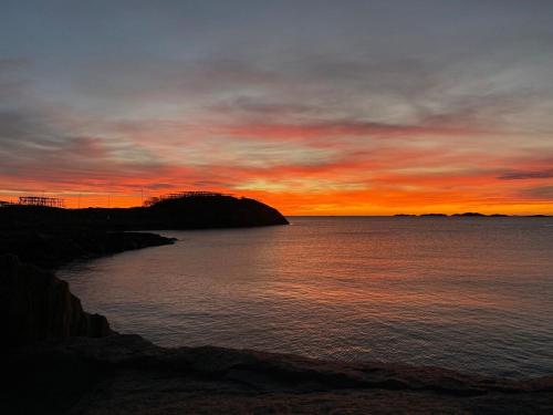 a sunset over a body of water with the sky at Apartment Vestpollen in Vestpollen