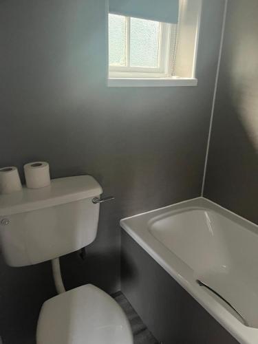 a bathroom with a toilet and a tub and a window at Moorville Hall Hotel in Stoke on Trent
