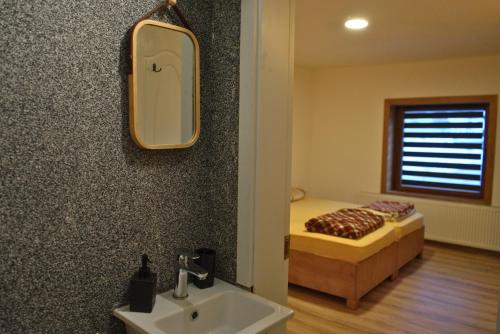 a bathroom with a mirror and a sink and a bed at Korja Apartments Mavrovo in Mavrovo