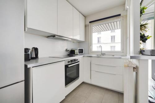 une cuisine blanche avec des armoires blanches et une fenêtre dans l'établissement PANTHEON MOUFETARD - Cosy Apartment, à Paris