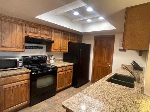 a kitchen with wooden cabinets and a black appliances at Snowed Inn in Brian Head