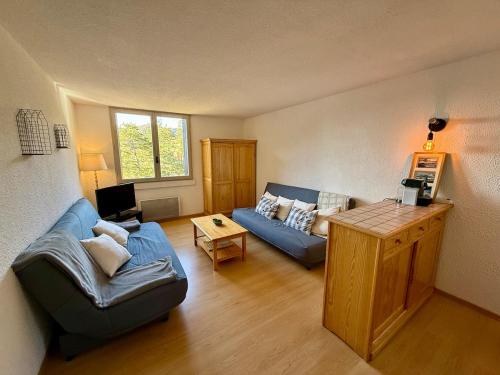 un salon avec un canapé bleu et une table dans l'établissement Coquet studio au pied des pistes, à La Colmiane