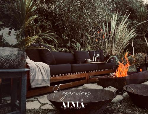 a couch sitting next to a fire in a yard at Alma Hotel in Campos do Jordão