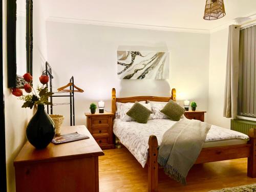 a bedroom with a bed and a table with a vase of flowers at Cosy 3BDR In Levenshulme-Close To Manchester City Centre And Stockport Town- Free Parking- WiFi in Manchester