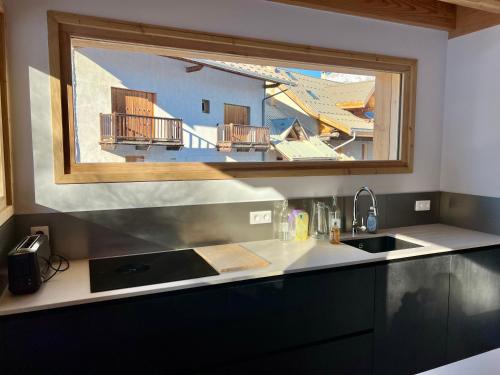 une cuisine avec un évier et une fenêtre dans l'établissement Chalet Neuf 12 pers Ski au pied, Cinéma, à Puy-Saint-Vincent