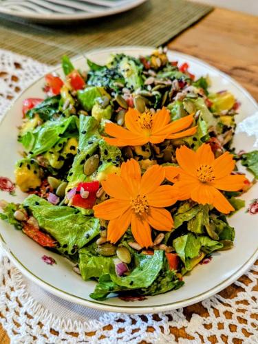a salad with orange flowers on a plate on a table at Casa das Irmãs - Só Mulheres - Women Only in Vale do Capao