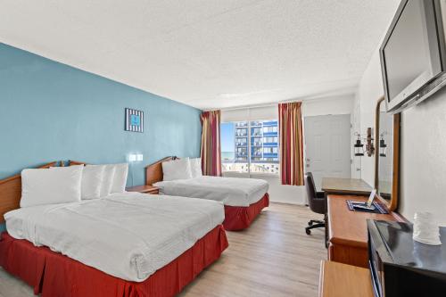 a hotel room with two beds and a flat screen tv at The Anchor Hotel in Myrtle Beach
