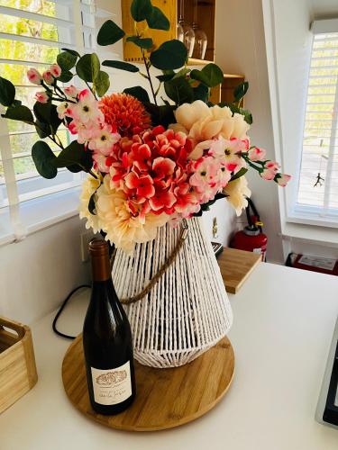 a bottle of wine and a vase with flowers at Chalet 190 La Belle Durbuy in Durbuy
