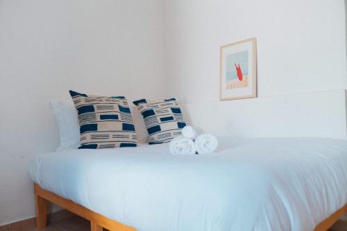 a white bed with blue and white pillows on it at Outsite Puerto Rico - San Juan in San Juan