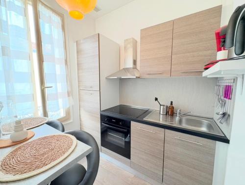 eine Küche mit Spüle und Tisch mit Stühlen in der Unterkunft "petillat"-Superbe studio meublé 3 étoiles in Vichy