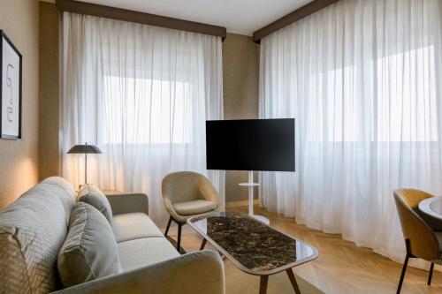 a living room with a couch and a flat screen tv at AC Hotel Milano by Marriott in Milan