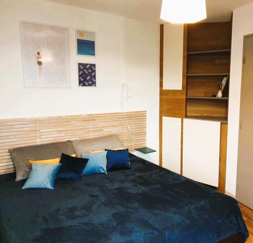 une chambre avec un grand lit avec des oreillers bleus dans l'établissement Appartement Arcachon centre proche plage 4pers, à Arcachon