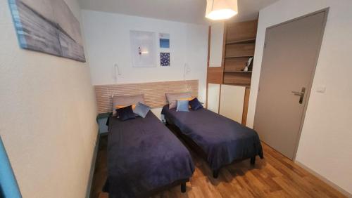 - 2 lits dans une petite chambre avec des draps violets dans l'établissement Appartement Arcachon centre proche plage 4pers, à Arcachon