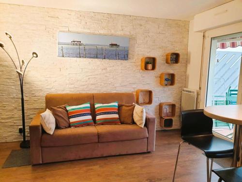 - un salon avec un canapé brun et un mur en briques dans l'établissement Appartement Arcachon centre proche plage 4pers, à Arcachon