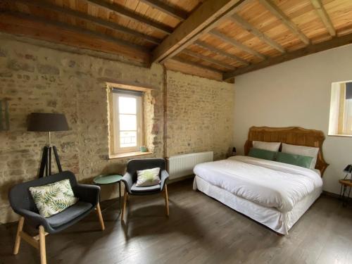 une chambre avec un lit et deux chaises dans l'établissement Ferme Hay Day, à Asnières-en-Bessin