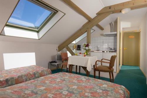 a room with two beds and a table and a kitchen at Gites de la Cascade in Le Tholy