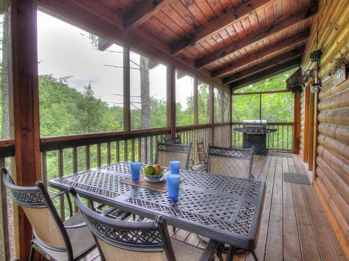 a table and chairs on a porch with a grill at 6BR close to PF Parkway- 2 hot tubs, game room, 4 decks, 3 living areas! in Pigeon Forge