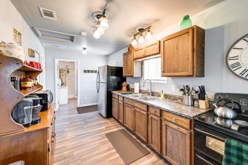 a kitchen with wooden cabinets and a large clock on the wall at Kingman Vacation Rental with Private Yard and Fire Pit in Kingman