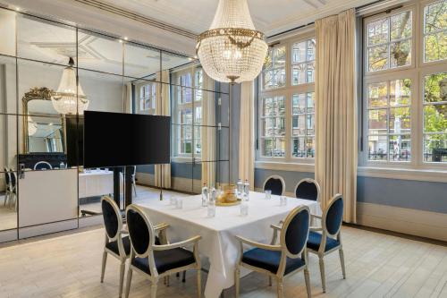 a dining room with a white table and chairs at The College Hotel Amsterdam, Autograph Collection in Amsterdam