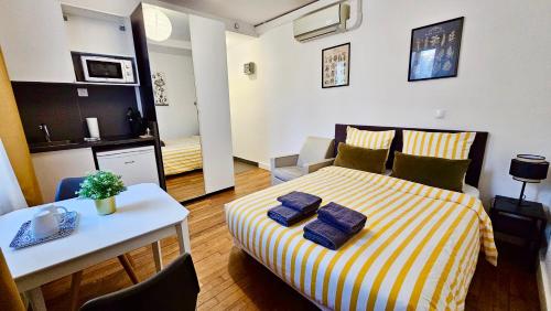 1 dormitorio con 1 cama con sábanas de rayas amarillas y blancas en Studio Safran - 15min Paris, calme & cosy, en Noisy-le-Sec