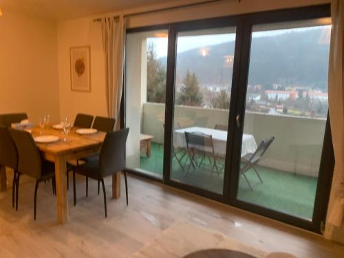 une salle à manger avec une table et des chaises et une grande fenêtre dans l'établissement La Résidence des Feutres app3 au RDC, à Gérardmer