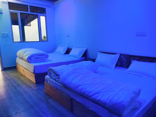 a blue room with two beds and a couch at Chaukhamba view Resort in Gupta Kāshi