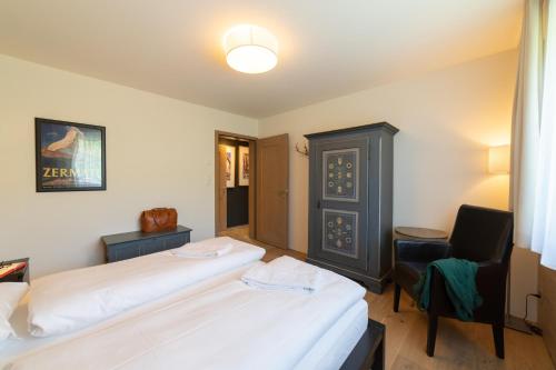 a hotel room with two beds and a chair at Primula in Wildhaus