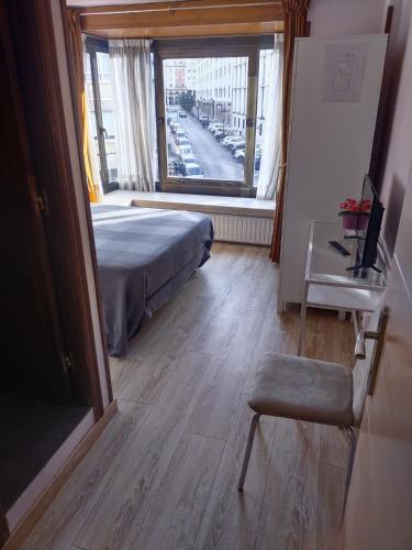 a bedroom with a bed and a window and a chair at Hostal Álvarez in Oviedo