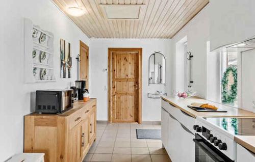 a kitchen with white walls and a wooden ceiling at Lovely House With A View Of The Limfjord in Øsløs