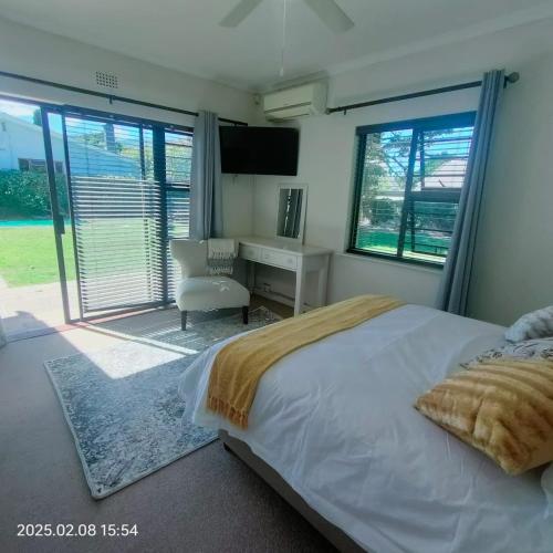 a bedroom with a bed and a desk and windows at Casa Alara warm and welcoming in Meadowridge