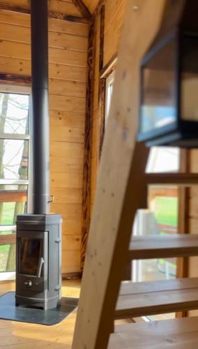 a wood stove in a log cabin with a staircase at Stodoła na drzewach in Justynów