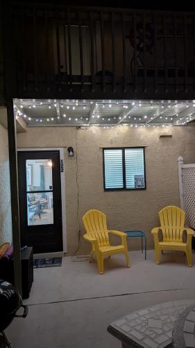 two yellow chairs sitting on a patio with lights at Double Take! Renovated Vacation Home in Panama City Beach