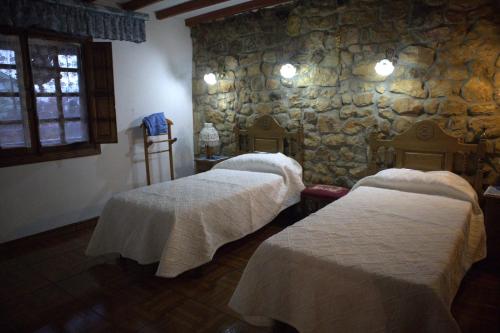 2 Betten in einem Zimmer mit einer Steinmauer in der Unterkunft Vivienda Quintana in La Cueva