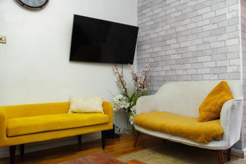 a living room with a yellow couch and a tv at 5 bedroom house near cardiff city. in Cardiff