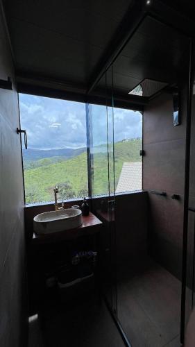 a bathroom with a sink and a large window at Cabana na Árvore com vista para SERRA da Canastra in São Roque de Minas