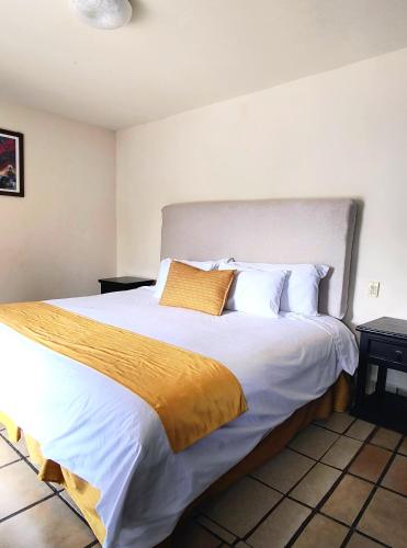 a bedroom with a large bed with white and gold sheets at Hotel Jardines del Centro in San Cristóbal de Las Casas