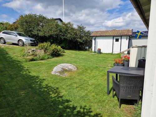 a table in a yard with a car in the background at Cabin at the sea close to public beach with a jumpingtower in Höviksnäs