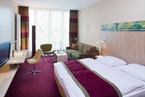 a hotel room with a bed and a couch at Mövenpick Hotel Frankfurt City Messe in Frankfurt/Main